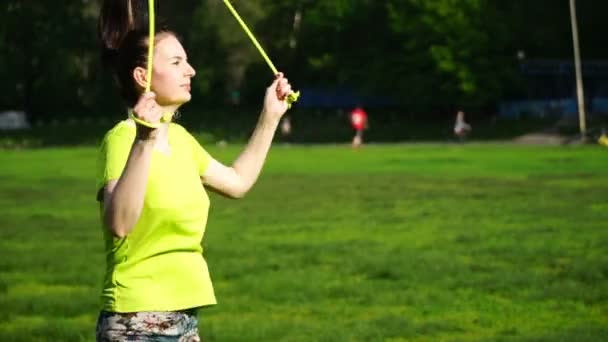 Запись женщина прыгает на скакалке в парке крупным планом — стоковое видео