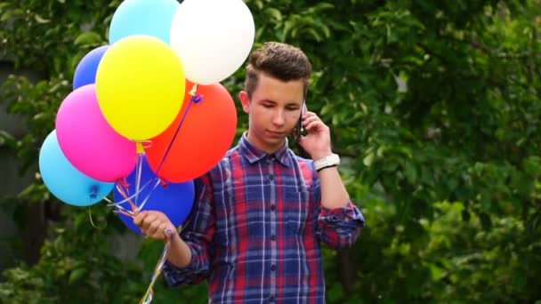 Footage young man holding balloons and talking on smartphone — Stock Video