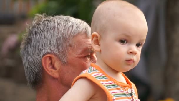 Footage grandfather holds grandson on hands in the open air, close-up. — Stock Video