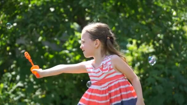 Film tjej blåser bubblor i parken. — Stockvideo