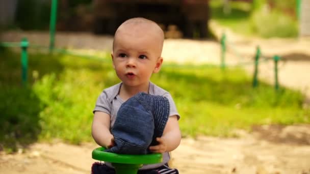 Footage liten pojke på leksaksbil utomhus. — Stockvideo