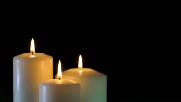 Filmaufnahmen brennender Kerzen isoliert auf schwarzem Hintergrund. 4k — Stockvideo