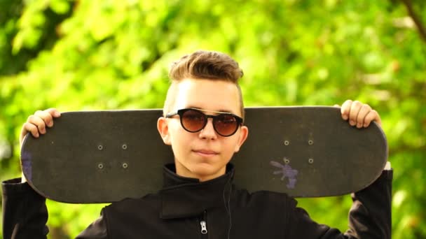 Filmato adolescente skateboarder in possesso di uno skate e guardando la fotocamera. 4K — Video Stock