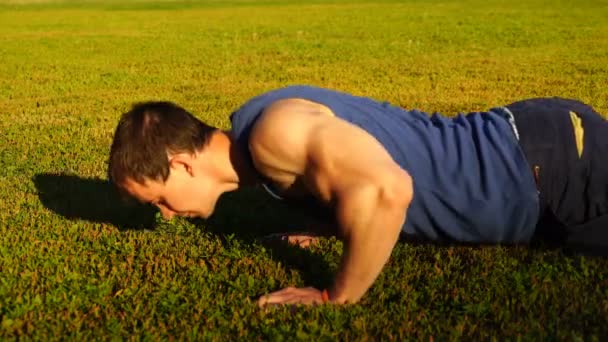 Caucasiano fitness man treinamento empurrar para cima exercício na grama. atleta masculino trabalhando ao ar livre. Vídeo 4K — Vídeo de Stock