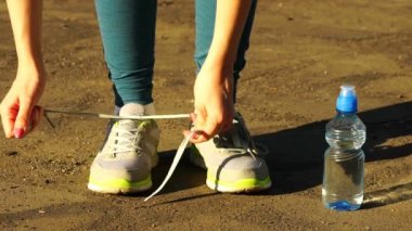 kız koşu ayakkabıları üzerinde dantel bağlamaya çalışan durdu. Fitness kız eğitim açık havada. HD 120fps