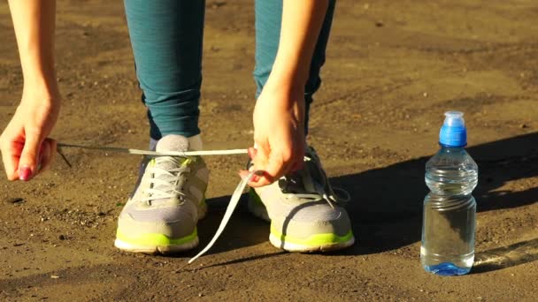 Dziewczyna zatrzyma się zawiązać sznurówki na buty do biegania. fitness dziewczyny szkolenia na zewnątrz. HD 120fps — Wideo stockowe