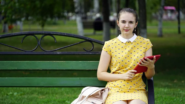 Femme assise sur un banc et utiliser l'application sur votre tablette — Photo