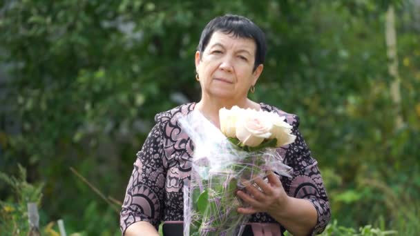 Footage elderly woman holding a bouquet of roses outdoors. 4K — Stock Video