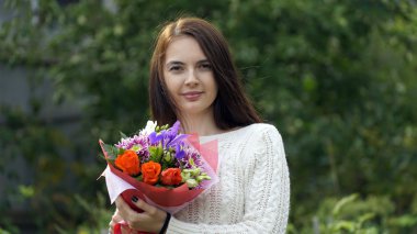 bir buket çiçek açık havada tutan kadın