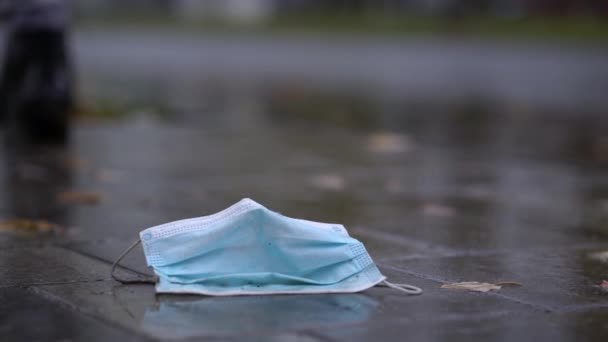 Mascarilla desechable usada en charco durante la lluvia — Vídeo de stock