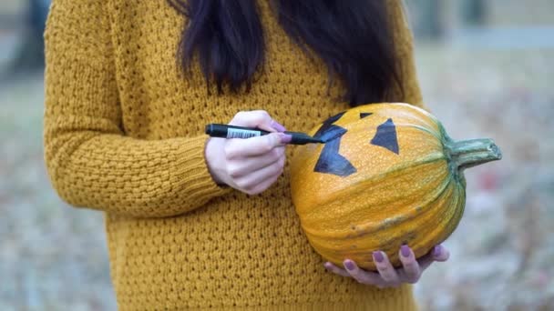 Közelkép nő kezek festeni narancs tök fekete festék őszi erdőben — Stock videók