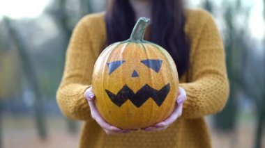 Sonbahar parkında balkabağı tutan kadın.