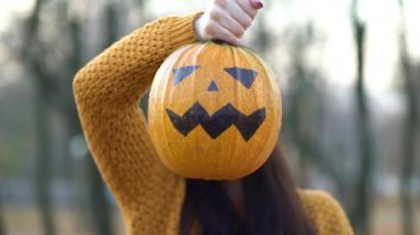 Sonbahar parkında balkabağı tutan kadın.