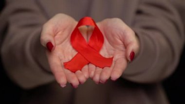 Dünya AIDS Günü için kadınların el desteği üzerine kırmızı kurdele.