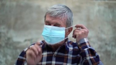 Yaşlı bir adam ikinci dalga karantina koronavirüsü COVID-19 salgınından korunmak için yüz maskesi kullanıyor..