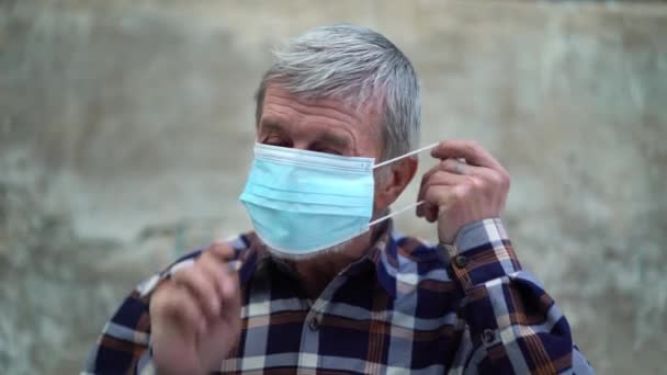 Een oude man gebruikt gezichtsmasker ter bescherming tegen het virus tegen de tweede golf quarantaine coronavirus COVID-19 pandemie. — Stockvideo