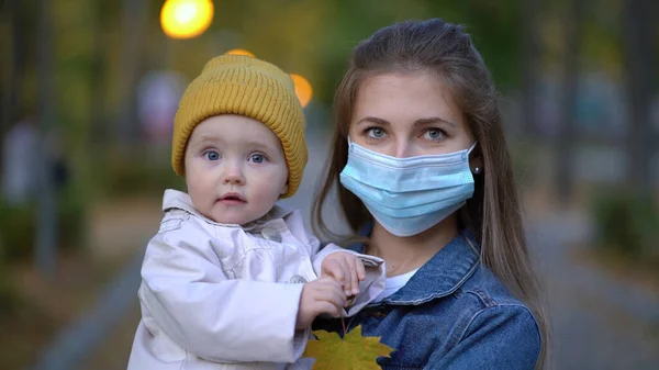 Masked mother holds hand lovely daughter on street walk during second wave quarantine coronavirus COVID-19 pandemic — Stock Photo, Image