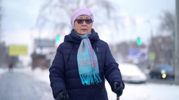 Aînée active formation femme âgée marche nordique avec bâtons de trekking. Femme âgée pratiquant la marche nordique à l'extérieur en hiver — Video