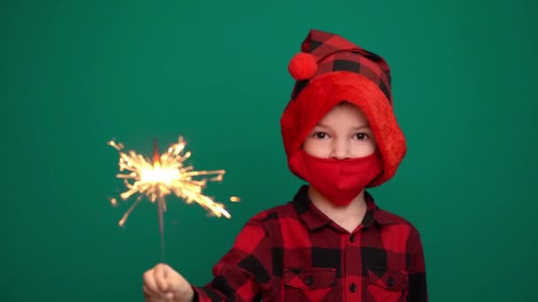 Мальчик с фейерверком и рождественской шляпой в защитной маске для коронавируса — стоковое видео
