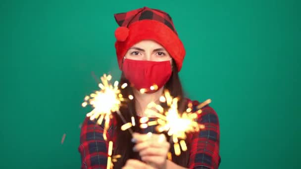 Havai fişek maytap ve Noel şapkalı güzel bir kadın. Coronavirus için koruyucu yüz maskesi takıyor. — Stok video