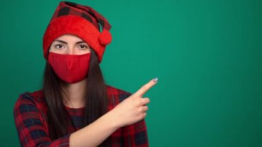 Noel Baba şapkalı ve maskeli kadın Coronavirus işaret parmağından korunuyor.