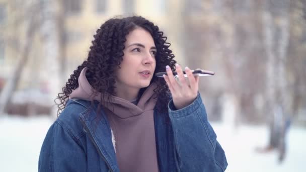 Retrato de mulher de cabelos encaracolados com telefone usando a mensagem de voz no inverno ao ar livre — Vídeo de Stock