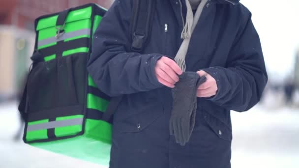 Курьер надевает перчатки на улице зимой — стоковое видео