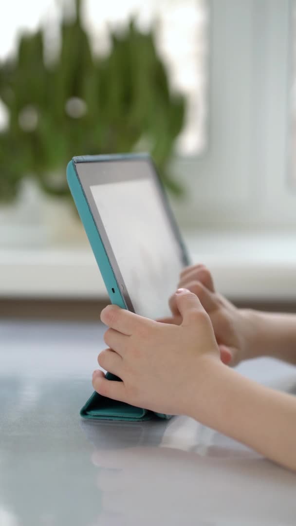 Předškolák sedí u stolu a dívá se na digitální tablet — Stock video