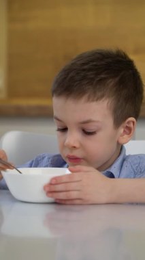 Küçük aç çocuk sabah süt ile mısır gevreği tadıyor..