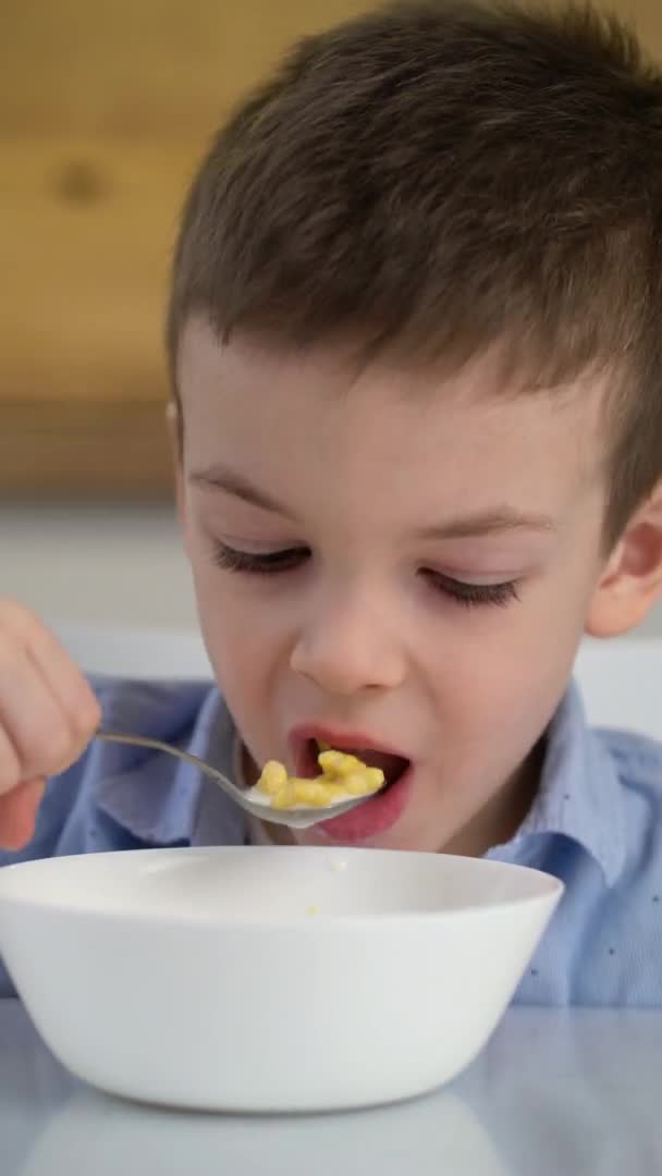 Small hungry boy eating tasting sweet corn flakes with milk at morning. — Stock Video