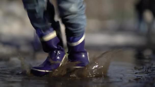 Happy boy rubber boots have fun playing in a puddle, on road — Stock video