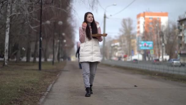 Jolie femme marchant à l'extérieur dans la ville et mangeant un hamburger — Video