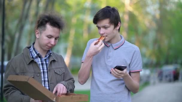 Dois amigos estão a comer pizza ao ar livre. Conceito de comida de rua — Vídeo de Stock