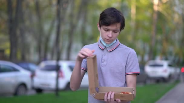 Mann nimmt Maske auf der Straße ab, um Pizza zu essen — Stockvideo