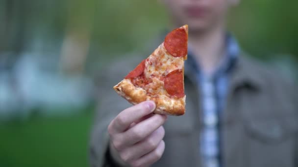 Nastolatek pokazuje a kawałek pizza dla w aparat — Wideo stockowe