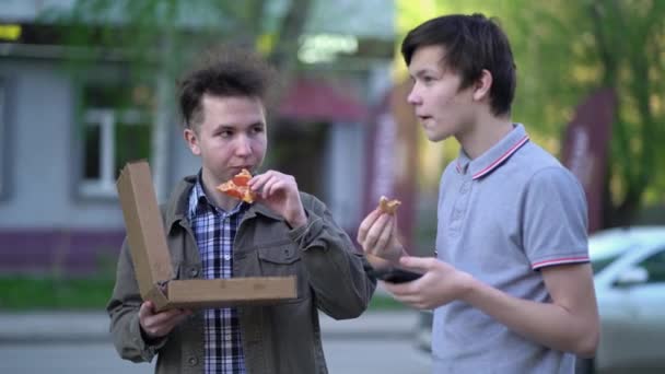 Dois amigos estão a comer pizza ao ar livre. Conceito de comida de rua — Vídeo de Stock