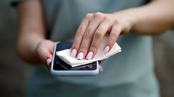 Mulher limpando telefone celular com um guardanapo — Fotografia de Stock