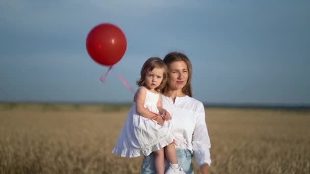 Matka z córką i balonami spacerującymi po polu pszenicy — Wideo stockowe