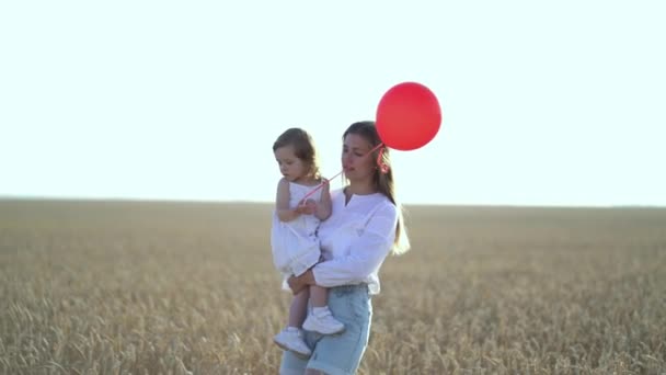 Madre con hija y globos caminando en el campo de trigo — Vídeos de Stock