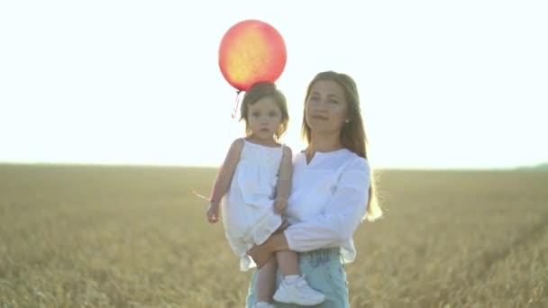 Matka z córką i balonami spacerującymi po polu pszenicy — Wideo stockowe