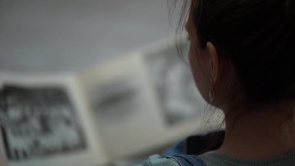 Kobieta patrząc na stary album fotograficzny swojej rodziny — Wideo stockowe