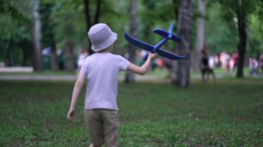 Parkta oyuncak bir uçakla oynayan çocuk.