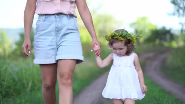 Szczęśliwa matka i córka z kwiatowym wieńcem spacerują po wsi — Wideo stockowe
