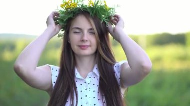 Kadın kafasına yabani çiçeklerden bir çelenk takıyor.