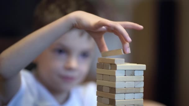 Chlapec hraje v deskové hře s dřevěnou věží doma — Stock video