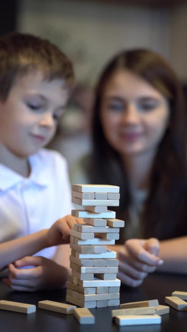Anne ve oğlu evlerinde tahta kuleyle masa oyunu oynuyorlar. — Stok video