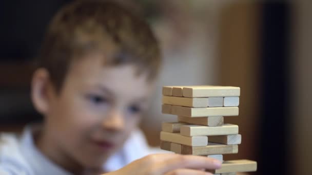 Pojke leker i brädspel med trä torn hemma — Stockvideo