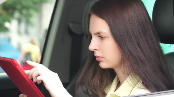 Νεαρός επιχειρηματίας που κάθεται σε ένα αυτοκίνητο και χρήση app σε το δισκίο — Αρχείο Βίντεο