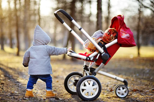 Småbarn pojke leker med sin barnvagn — Stockfoto