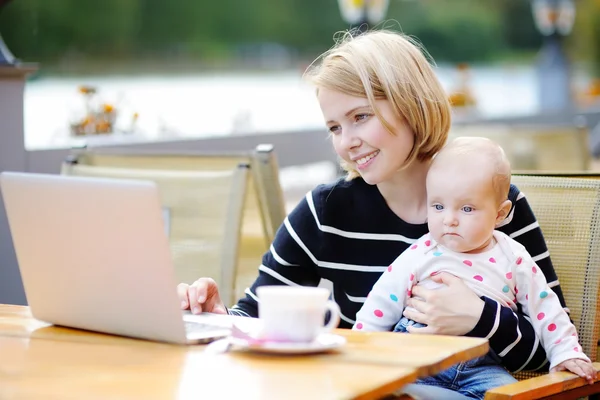 Giovane madre con il suo bambino che lavora o studia sul computer portatile — Foto Stock